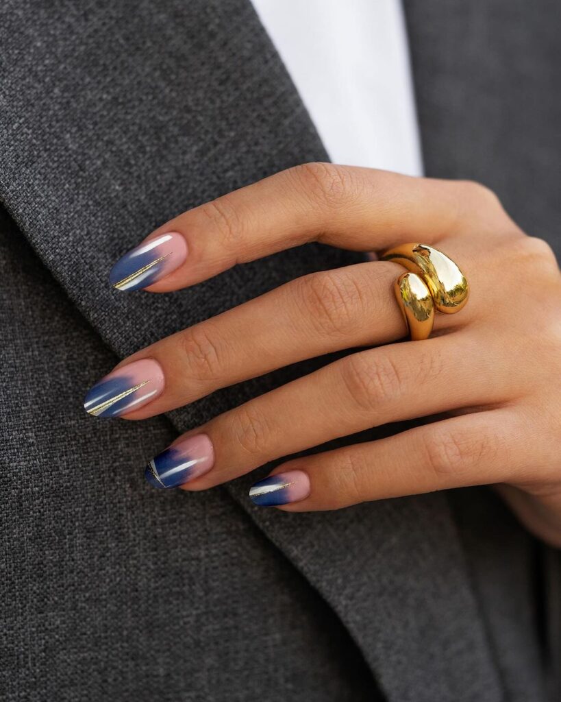  nail design featuring a blue ombre gradient with metallic accents and a gold stripe, capturing the sophistication of autumn evenings