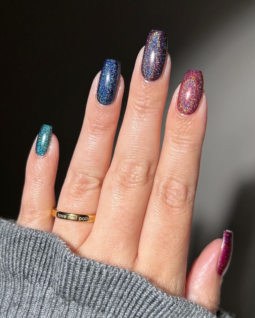 Dazzling fall nail design with glittery galaxy-inspired hues, featuring deep blues, rich purples, and reds, creating a mesmerizing effect