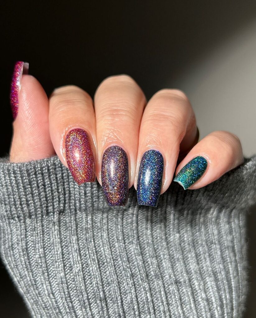 Dazzling fall nail design with glittery galaxy-inspired hues, featuring deep blues, rich purples, and reds, creating a mesmerizing effect