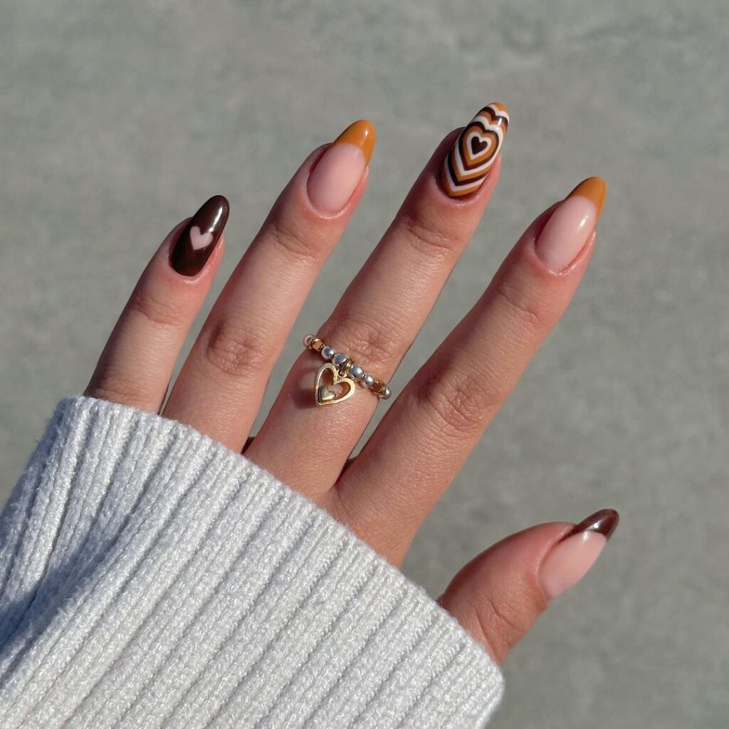 Warm & cozy nail design featuring chocolate browns, caramel swirls, and heart accents for a sophisticated autumn look.